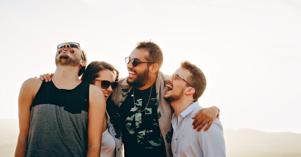 A group of young adults laughing and enjoying time together outdoors under the sun.